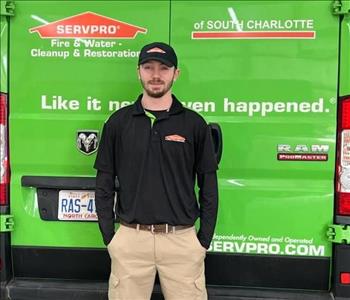 SERVPRO of South Charlotte employee, in uniform, standing in front of a green work van.