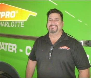 Photo of male SERVPRO of South Charlotte employee Juan Artiles in front of green SERVPRO van